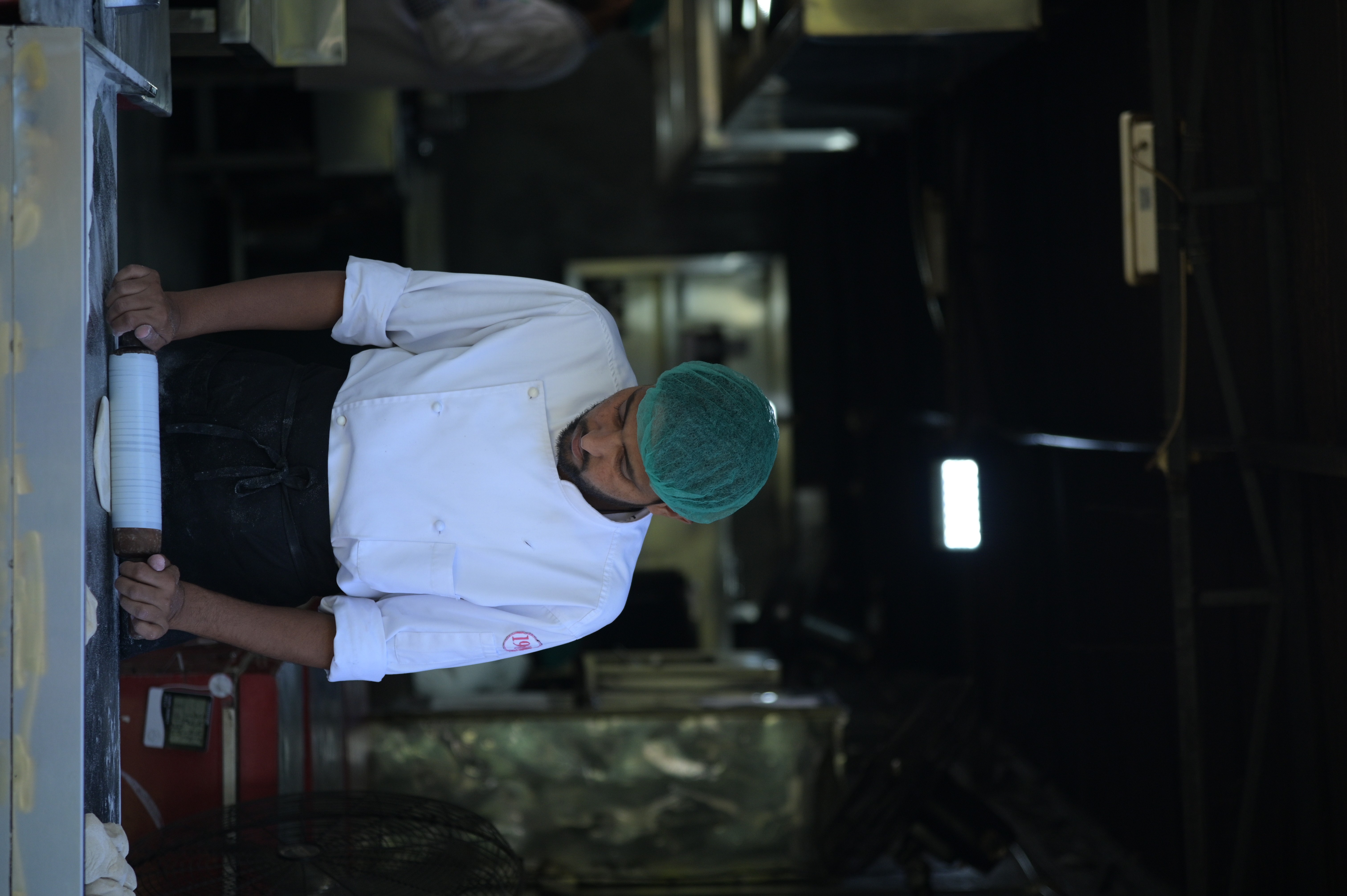 A man making naan (flatbread) which is leavened, oven-baked or taw