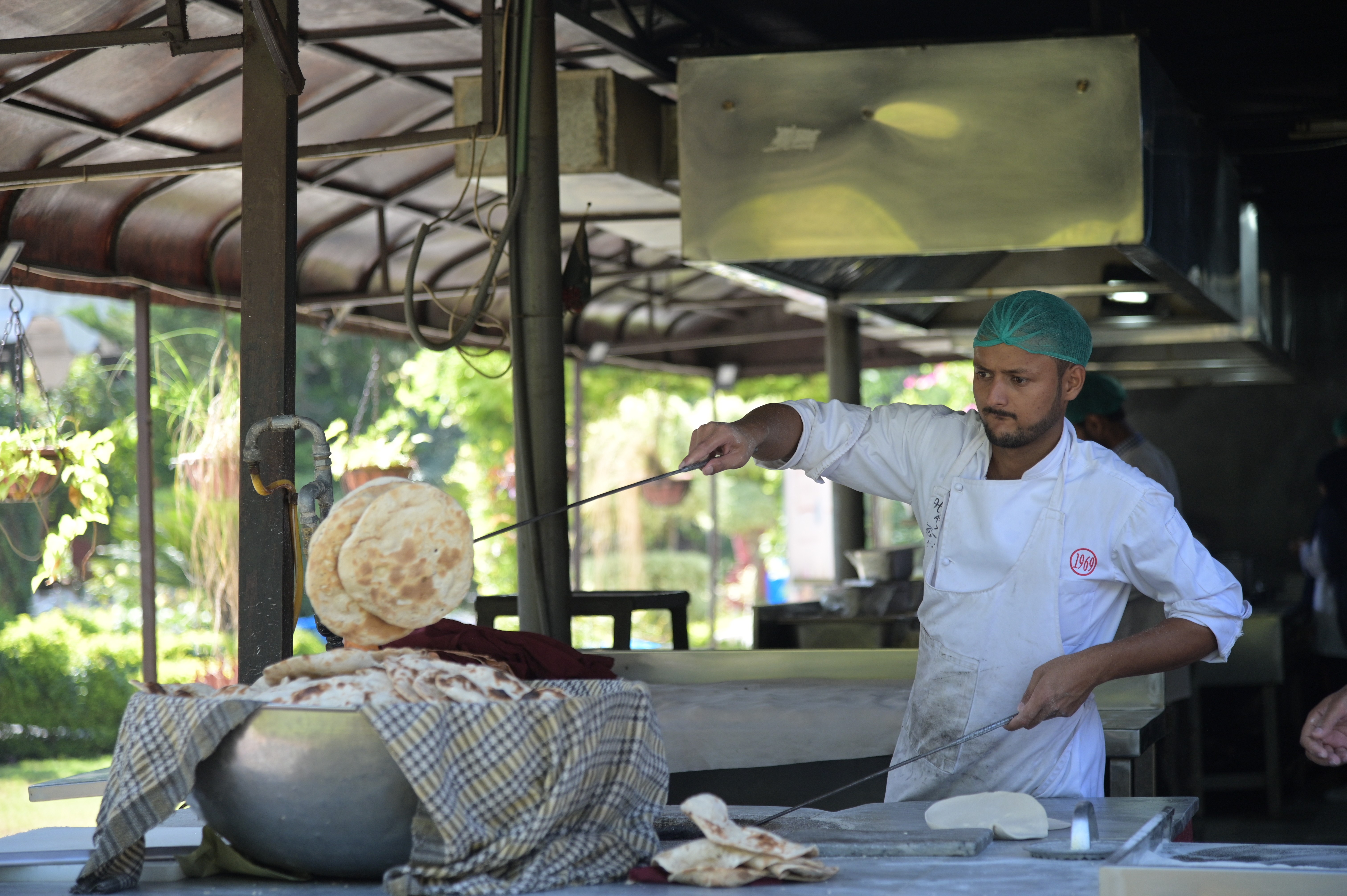 A man making naan (flatbread) which is leavened, oven-baked or tawa-fried.