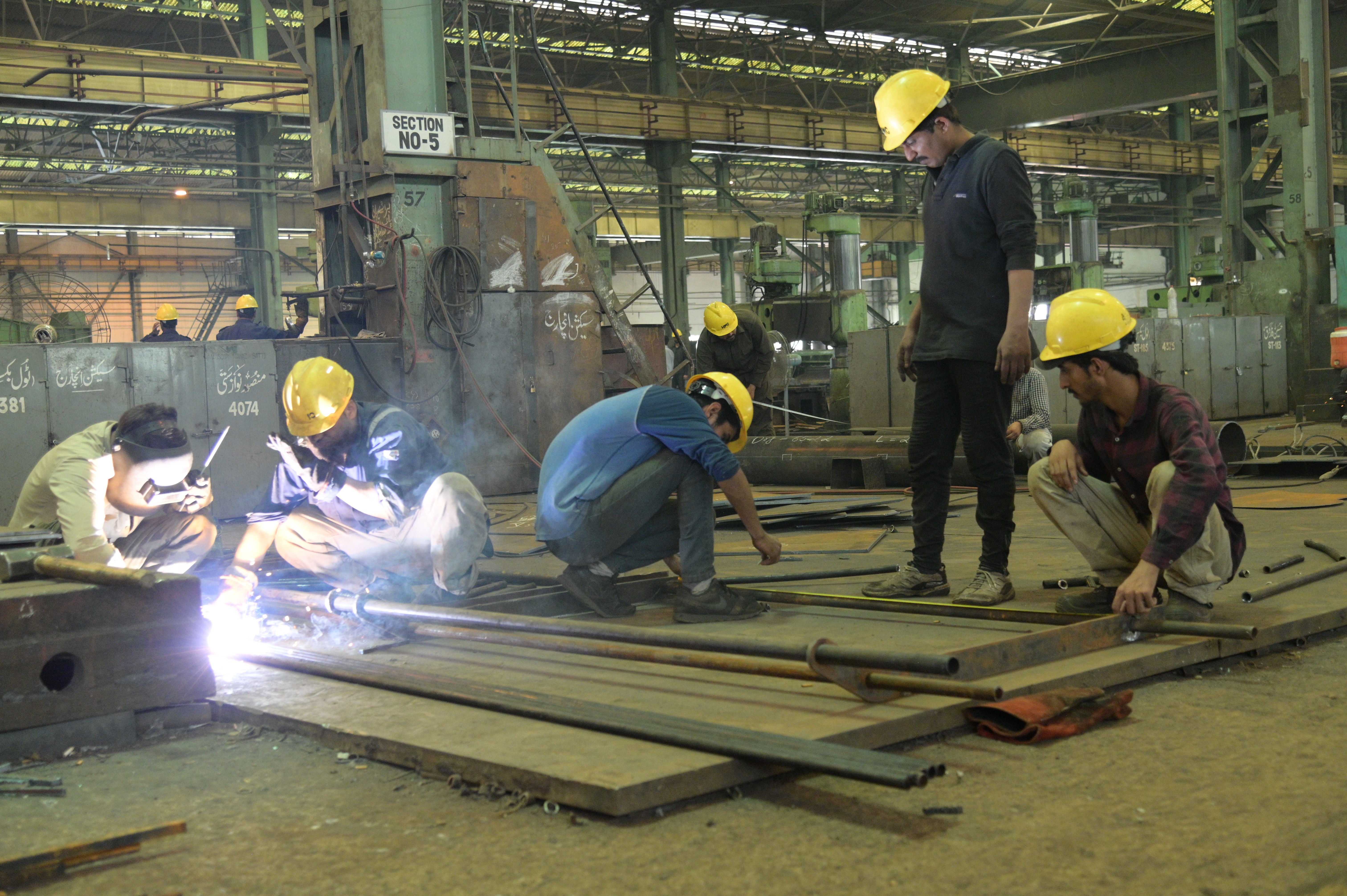 Workers welding the cylindrical pipes