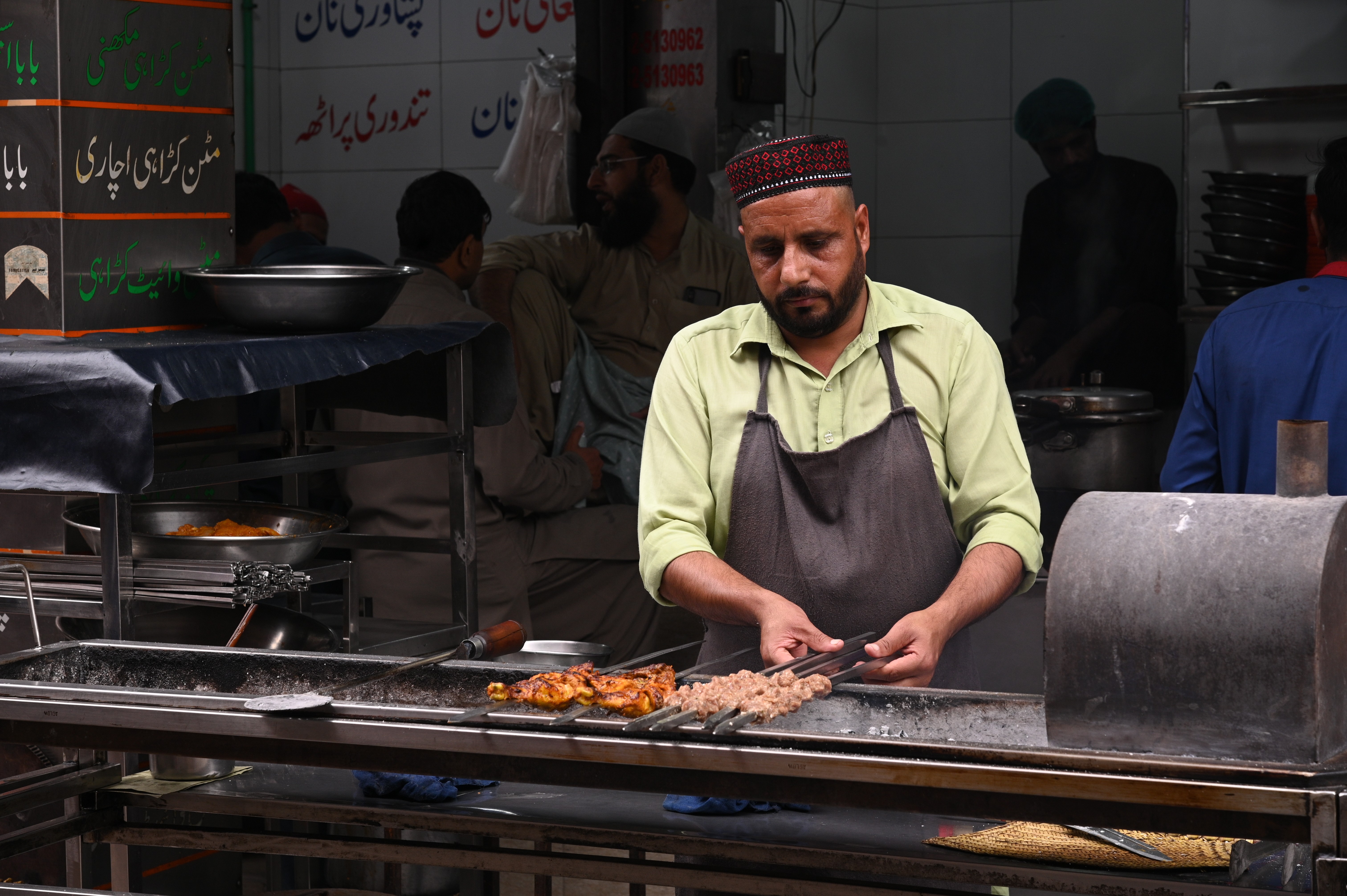 A chef preparing BBQ chicekn and seekh kabab (native to the subcontinent, made with spices, spiced minced or ground meat, usually lamb, beef, or chicken, formed into cylinders on skewers and 