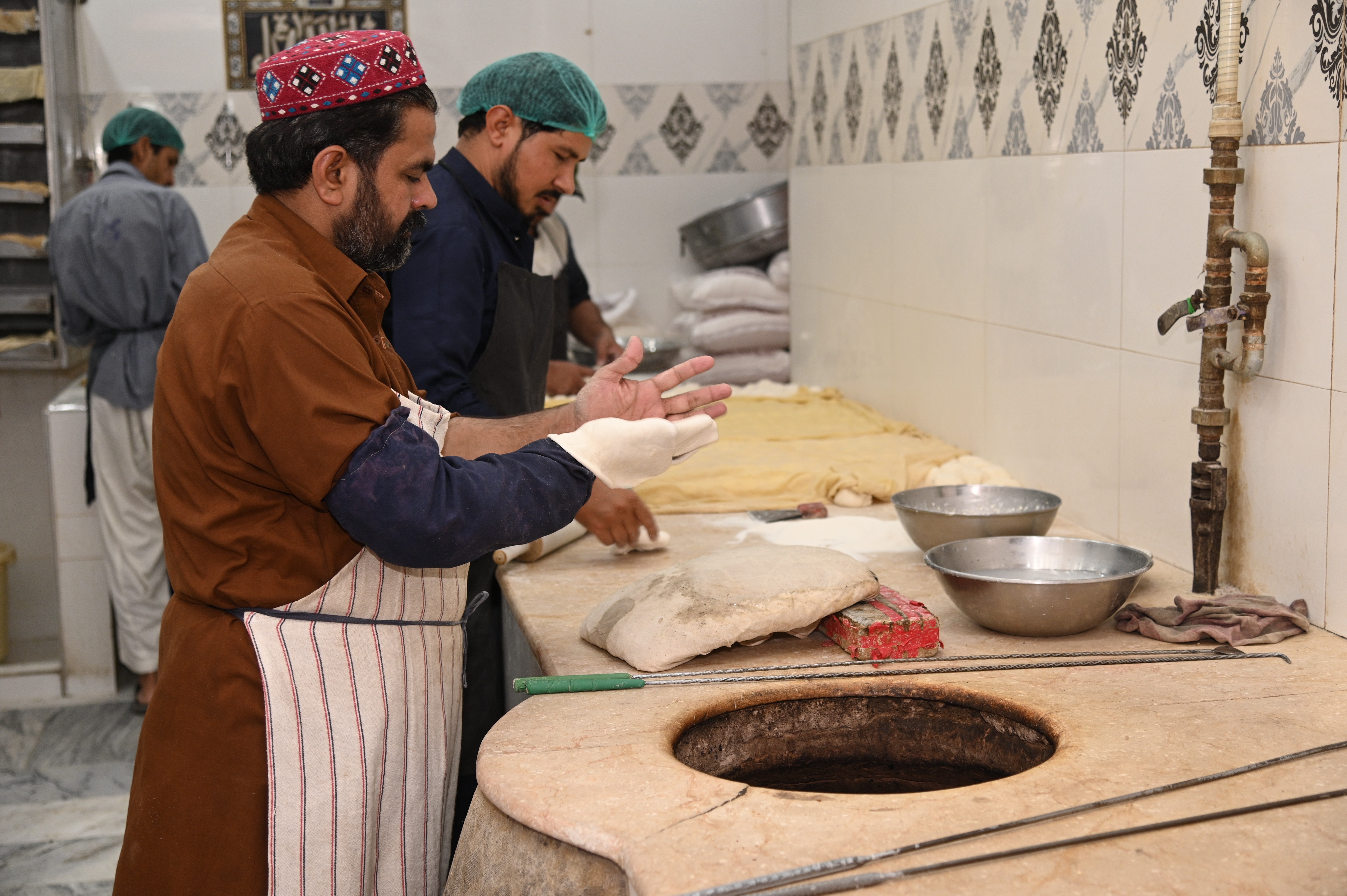 A man making naan (flatbread) which is leavened, oven-baked or tawa-fried.