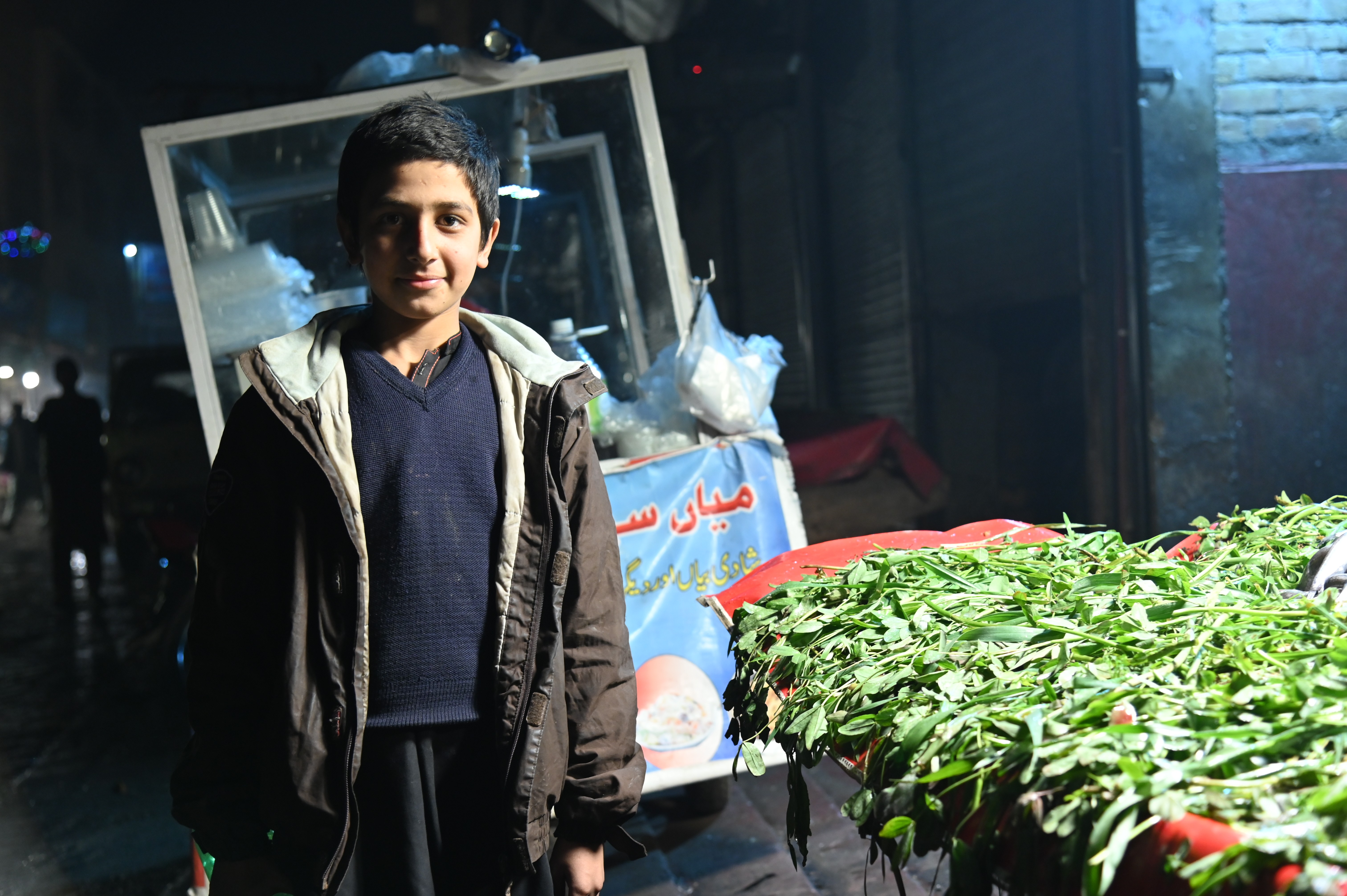 A boy with his stall of fresh green leaf vegetables