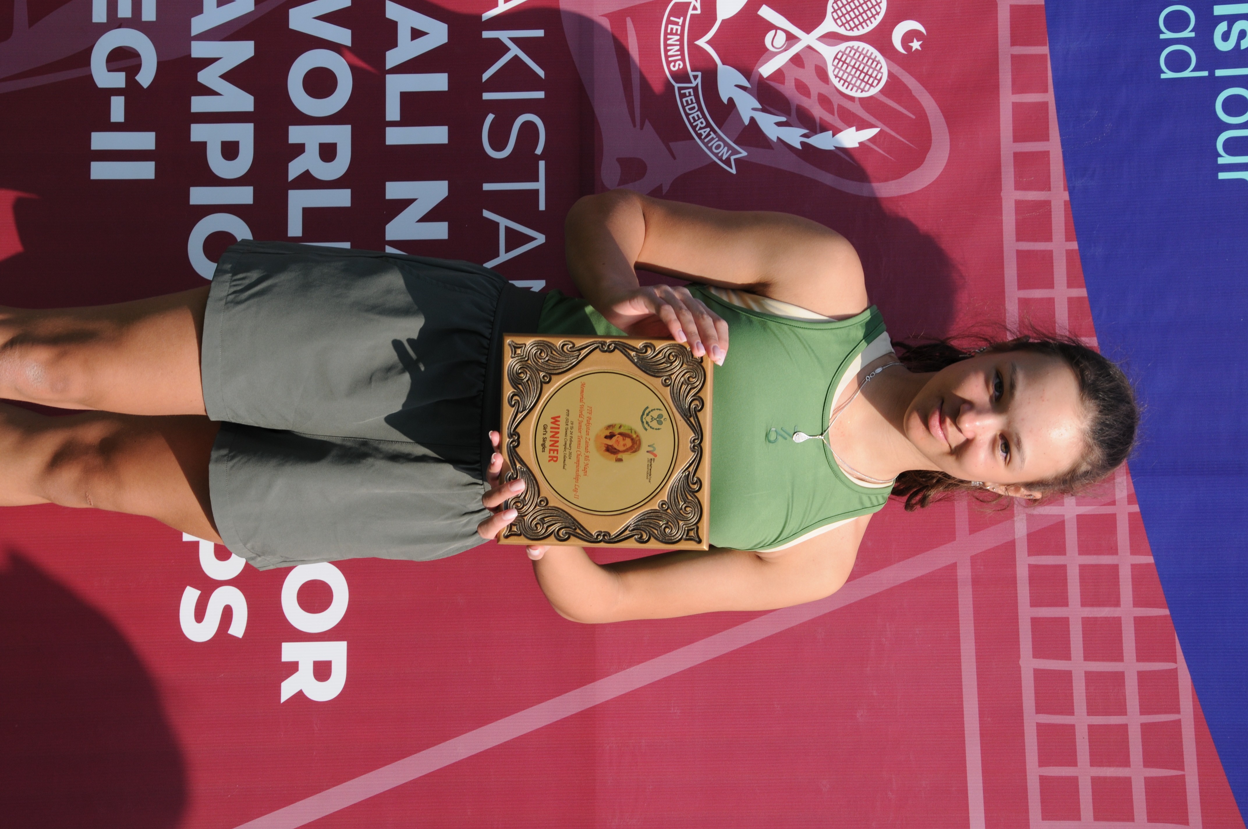 A winning tennis player posing with her trophy