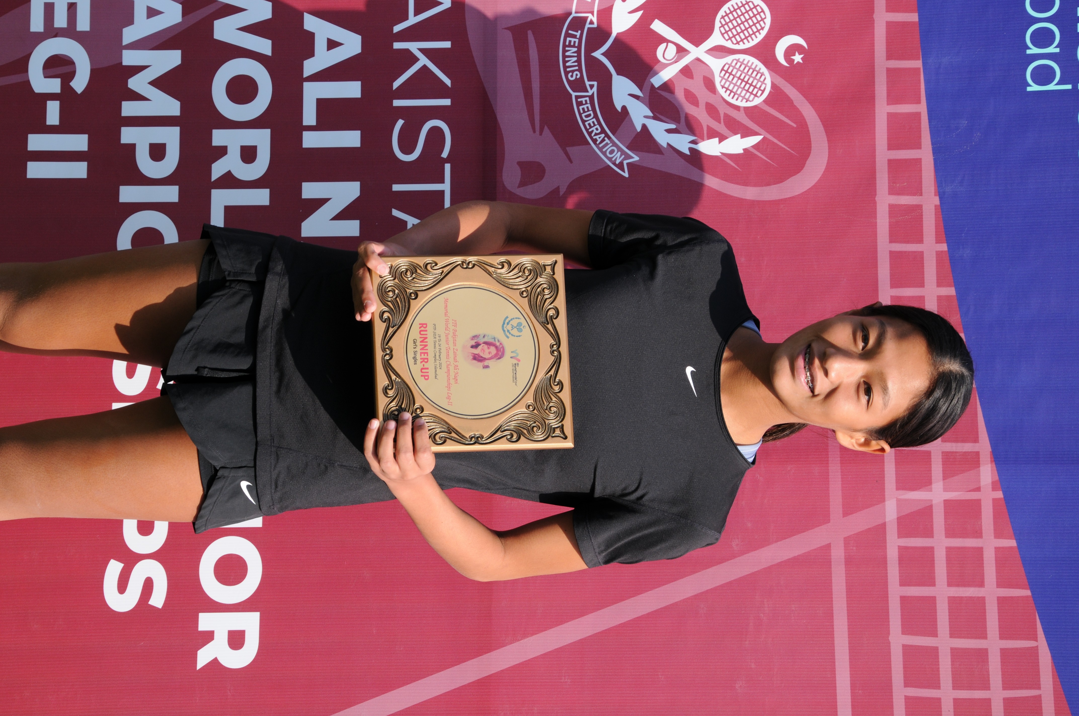 A winning tennis player posing with her trophy