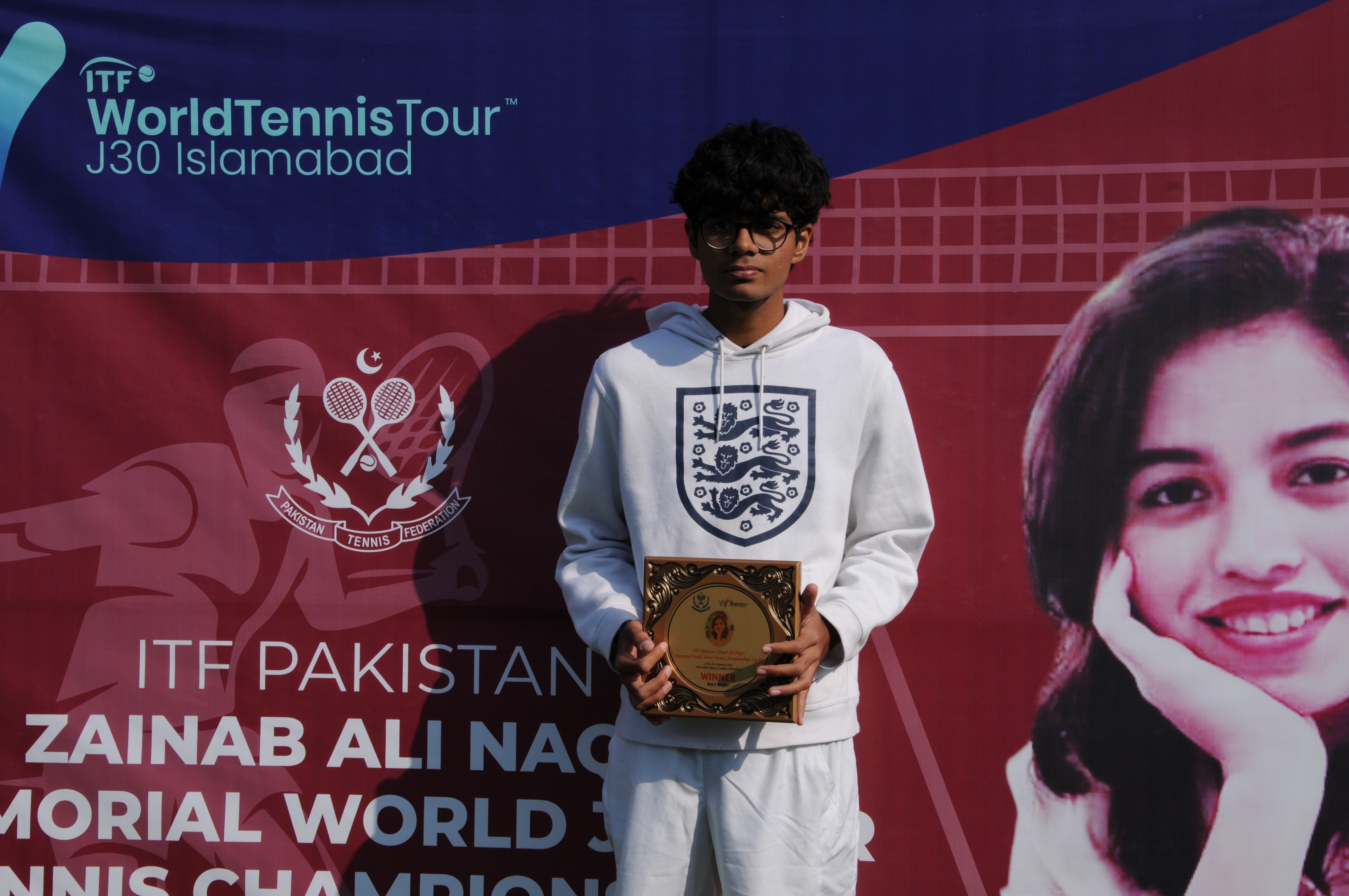A winning tennis player posing with his trophy
