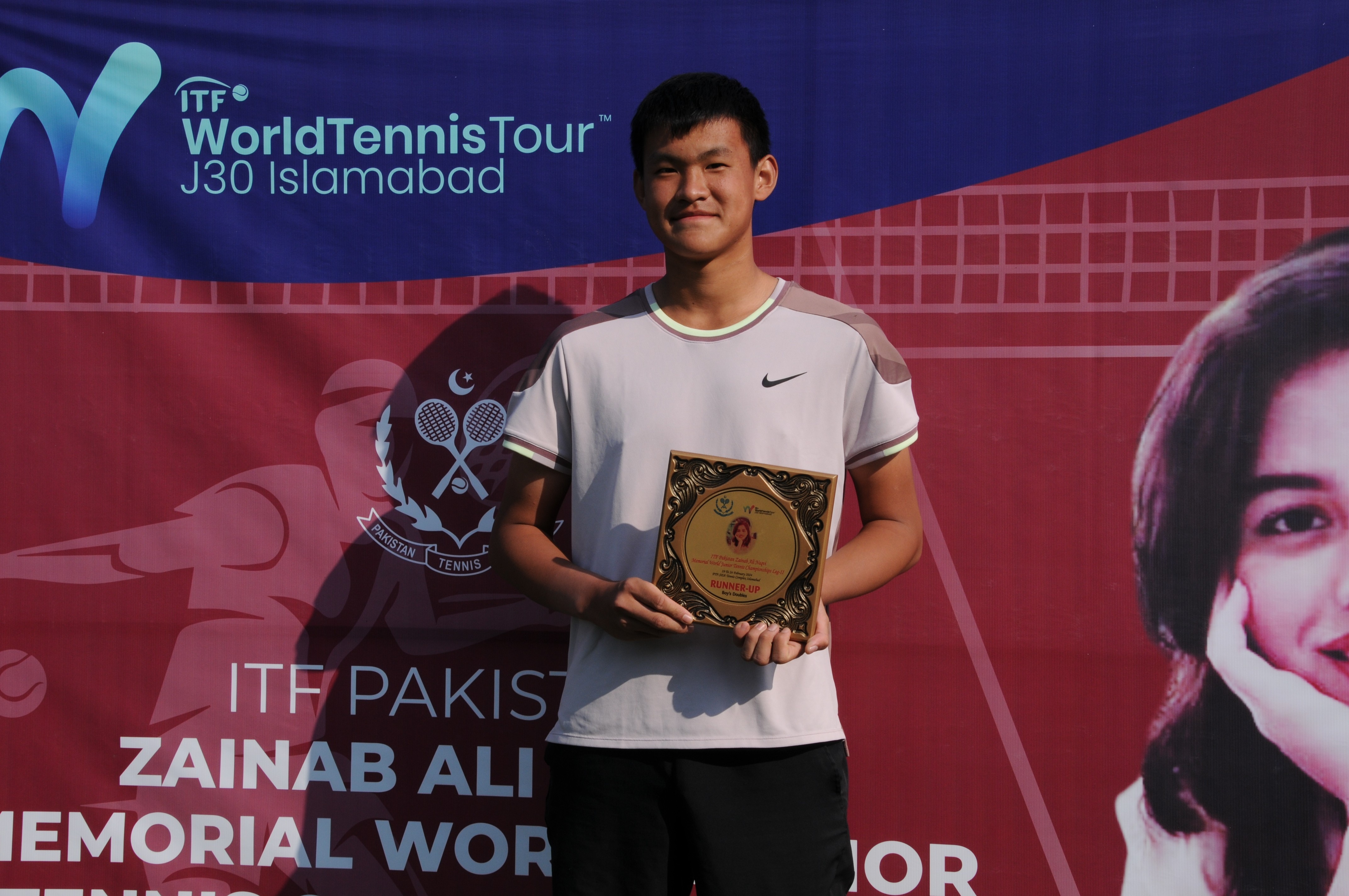 A winning tennis player posing with his trophy