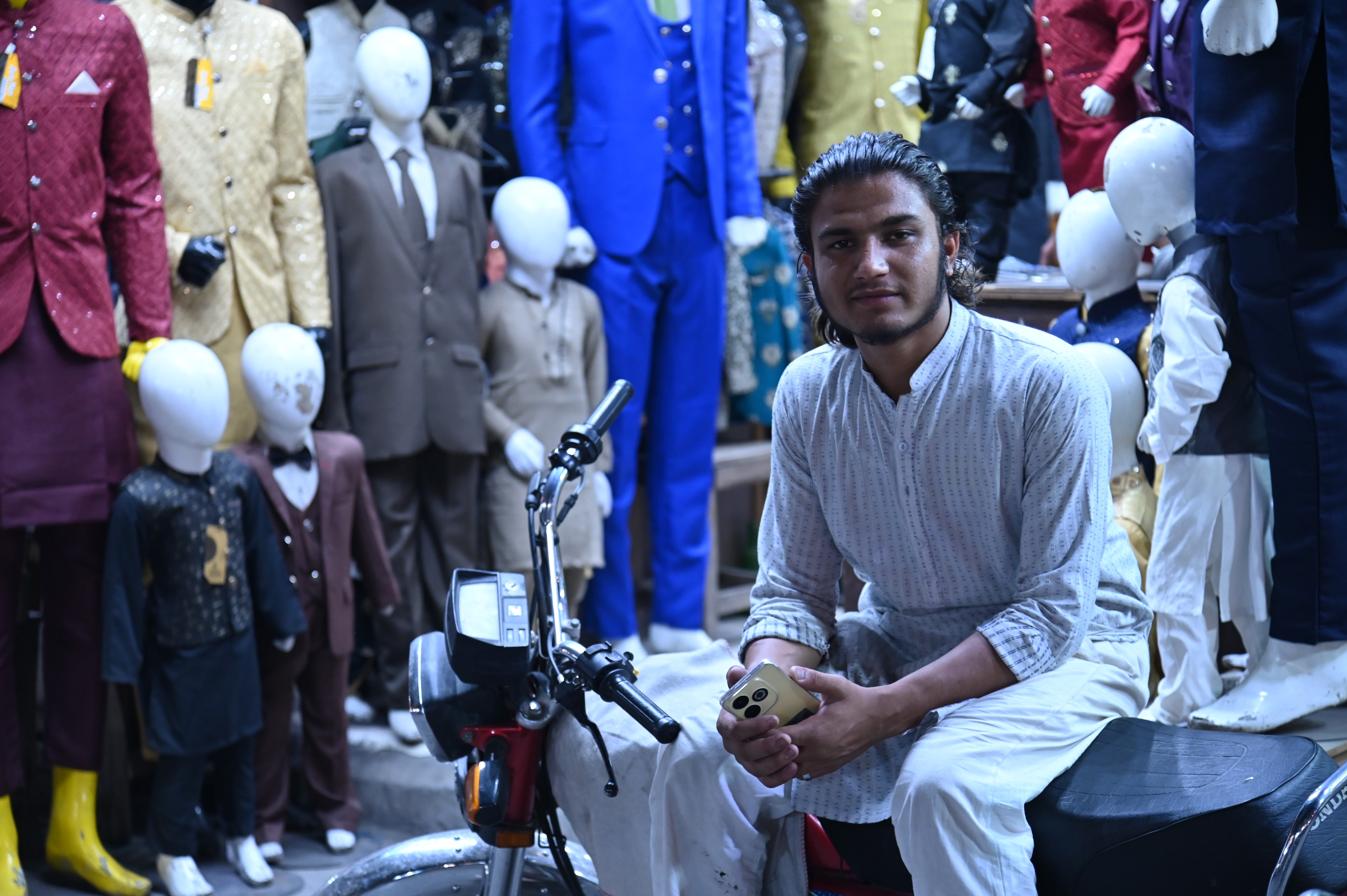 A boy sitting outside his shop