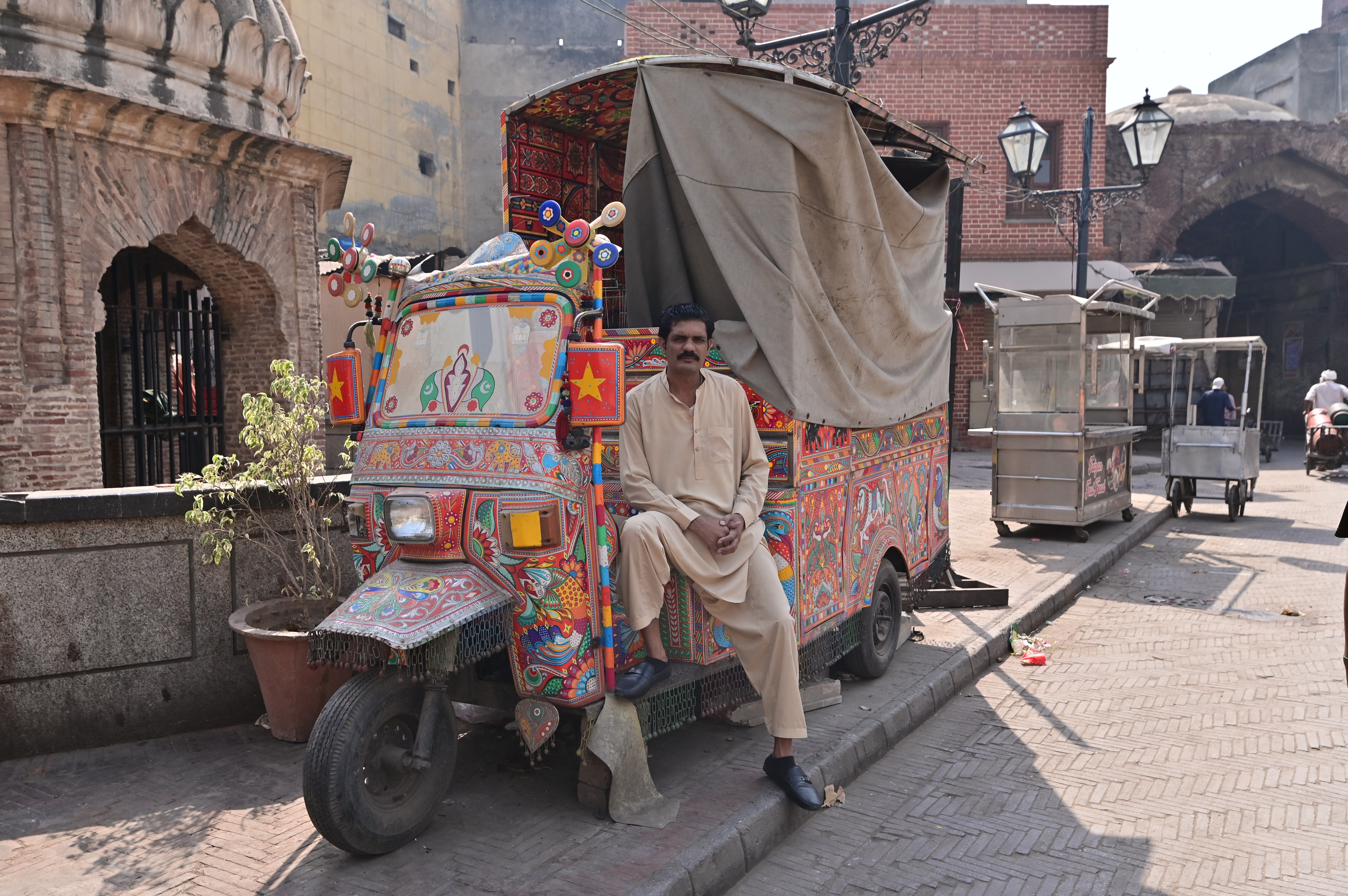 A man posing with his decorated rikshaw