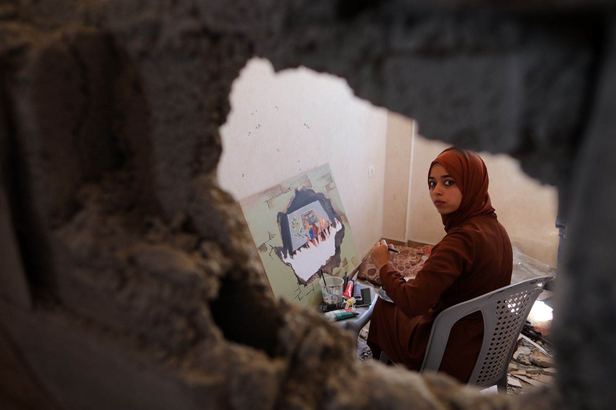  غزہ کی پٹی کے جنوبی شہر خان یونس میں ایک فلسطینی فنکارہ کو مقتول فنکار دونیانا الامور کے تباہ شدہ گھر میں مصوری کرتے ہوئے دیکھا جاسکتا ہے۔ (شِنہوا)